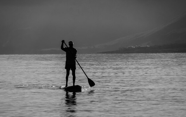 Man paddleboarden in de zee tegen de berg