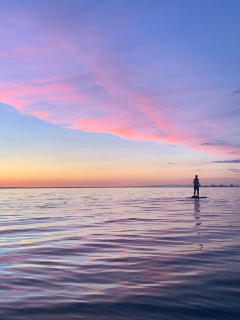 Man paddleboarding on lake against sky