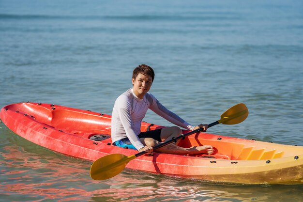 写真 海でカヤックボートを漕いでいる男