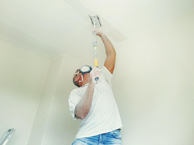 Photo man painting ceiling at home