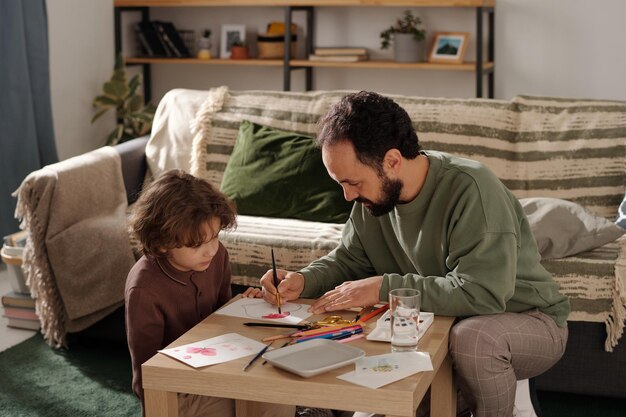 Photo man painting heart on handmade postcard