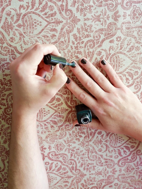 Man painting his fingernails in black colour at home Male manicure Concept of self care