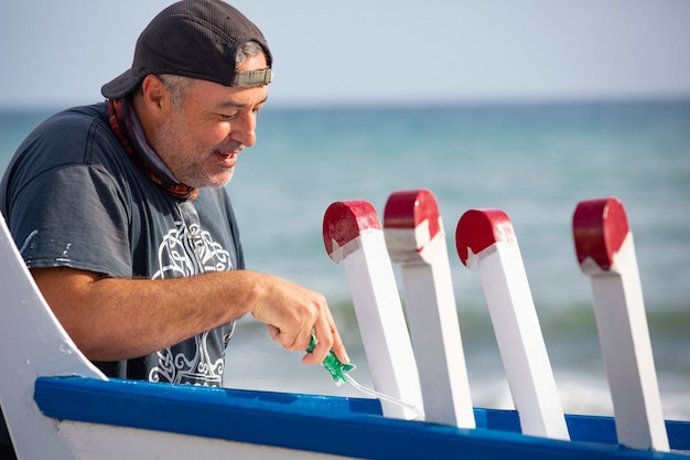 man painting traditional row boat with brush