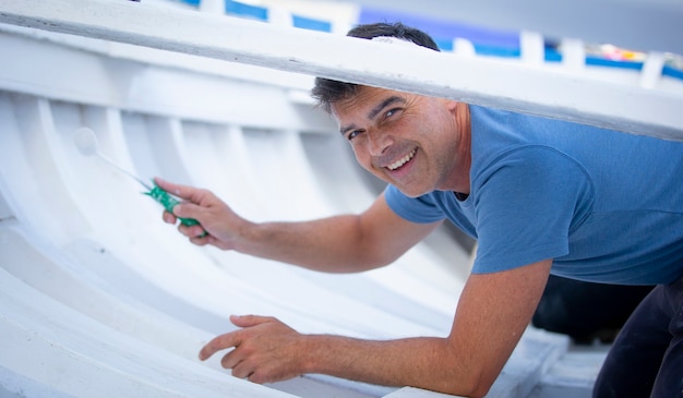 man painting traditional row boat with brush