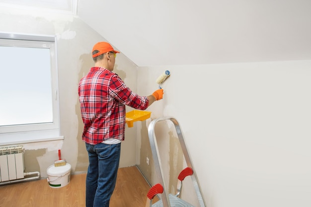 Man painting wall with roller banner with place for text