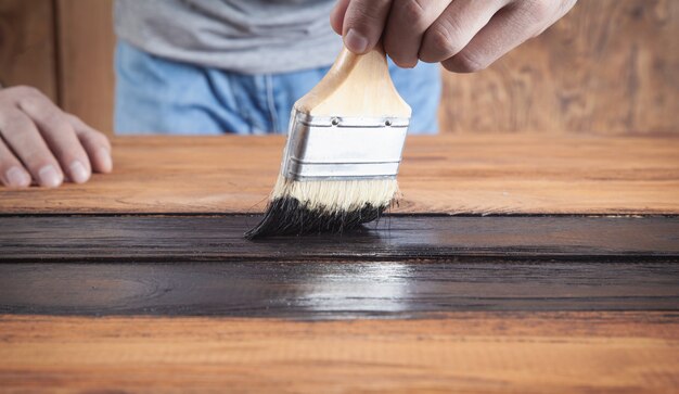 Man painting wood with a brush.