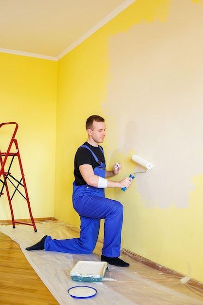 A man paints the wall in the house with a roller and paint.\
renovation of rooms in the house.
