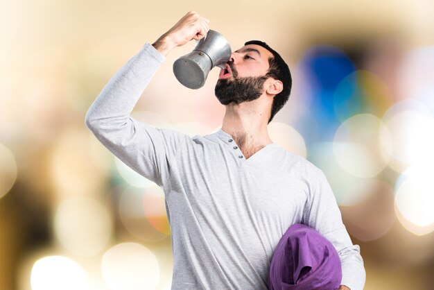 Man in pajamas holding a coffee pot on unfocused background