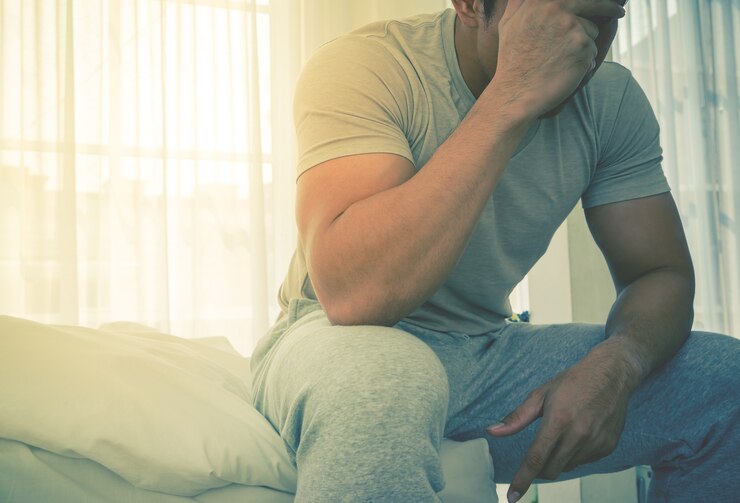 パジャマの男性は、ベッドで頭がおかしくなり、朝にストレスがかかる