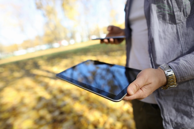 Photo man in pakr hold digital tablet pc with blank screen