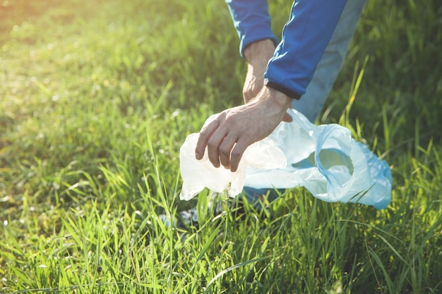 Man pakt een plastic zak uit graspark.