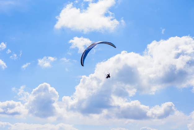 Uomo su un paracadute che vola in chiaro cielo