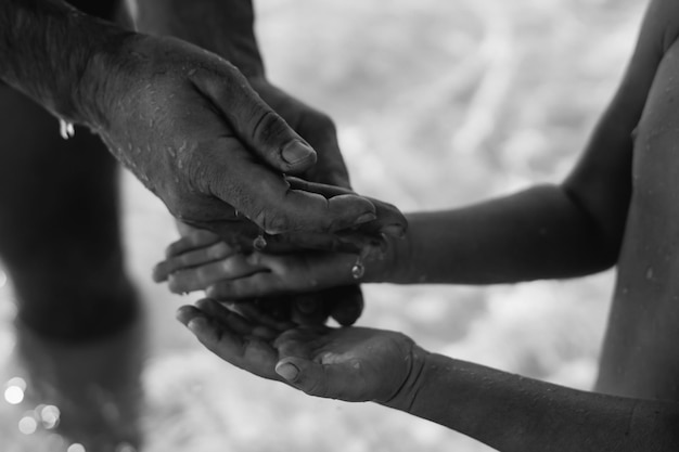 Foto l'uomo passa le gocce d'acqua al bambino tenere la mano prendere il liquido sul palmo aperto la vera bellezza della natura nel braccio maschio forte del papà mare limpido preservare l'acqua pura salva proteggere insieme il padre ama prendersi cura del bambino