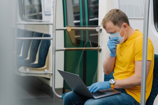 Man passagier hoest en heeft luchtwegaandoeningen, reist met het openbaar vervoer, gebruikt een laptopcomputer