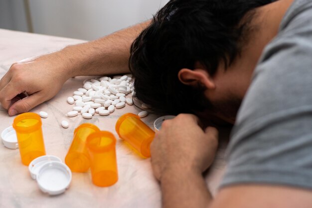 Man passed out on table for overdose of drugs with empty bottles and drugs on table