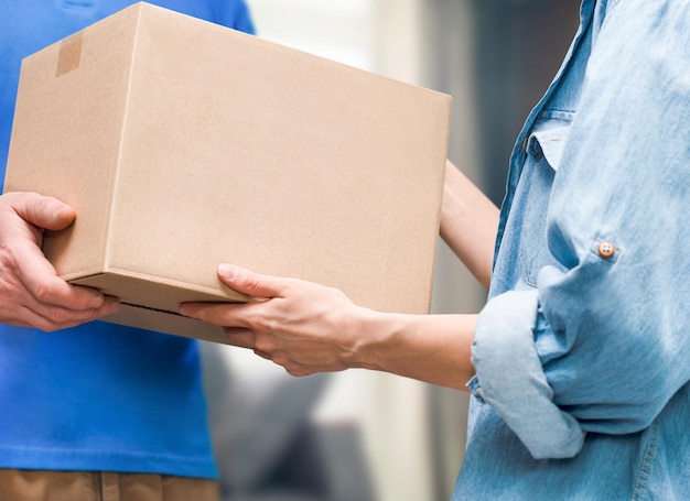 A man passes a cardboard box to a woman's hands closeup