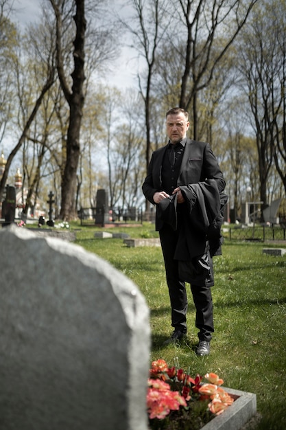 Мужчина отдает дань уважения надгробной плите на кладбище