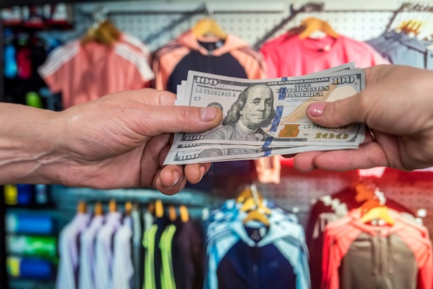 Man pays in dollars for buying clothes in a store. shopping concept