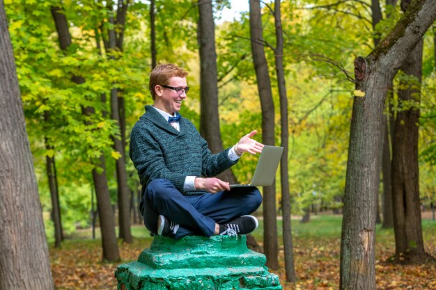 Un uomo su un piedistallo che finge di essere una statua nel parco autunnale.
