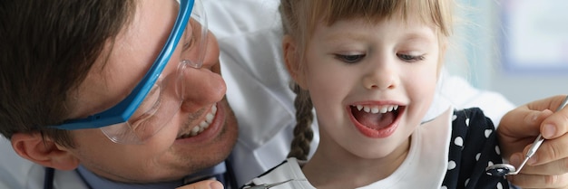 Photo man pediatrician check little girls health condition using special tool for mouth