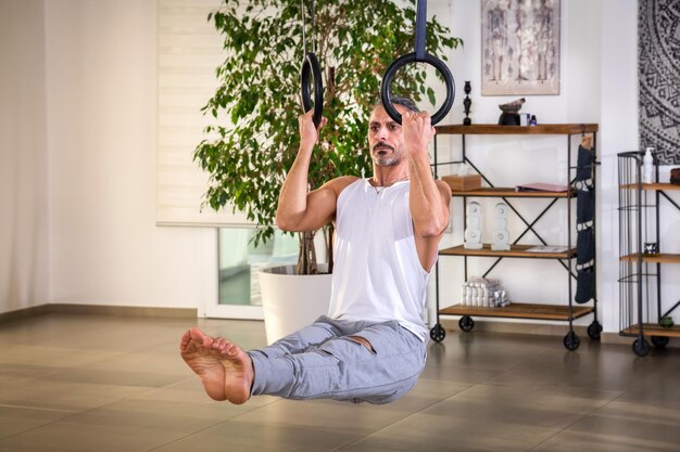 Man performing calisthenics L sit exercise with steady rings