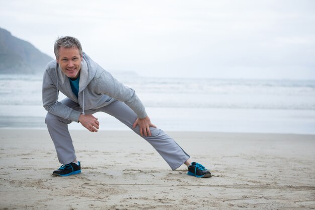 Uomo che esegue allungando esercizio sulla spiaggia