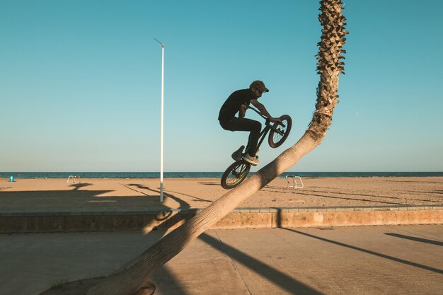 Photo man performing stunt with bicycle against clear sky