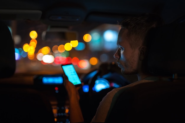 The man phone inside a modern car in the night city. Left side traffic