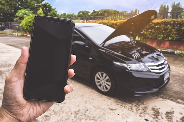 壊れた車で助けを求めて電話をかける男