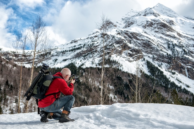 Il fotografo dell'uomo scatta foto tra le montagne innevate