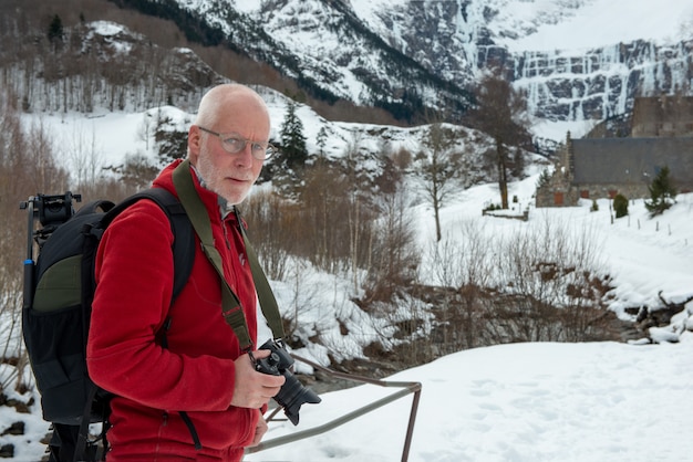 Man photographer with camera in the snowy mountain