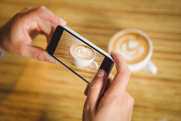 Man photographing his cappuccino with coffee art