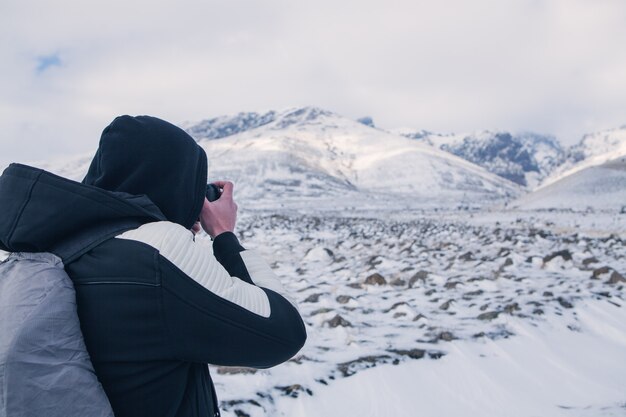 A man photographing a mountain under the snow