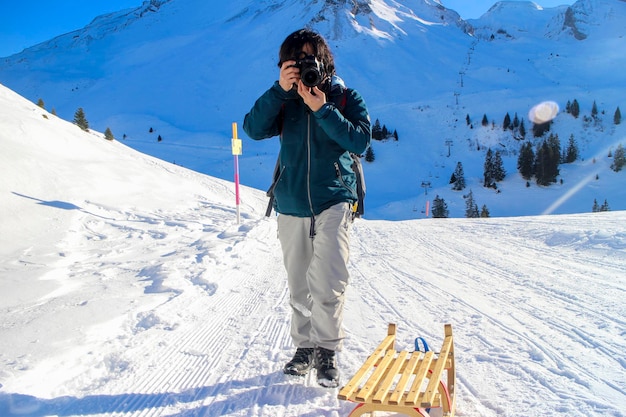 写真 雪で覆われた山で写真を撮っている男性