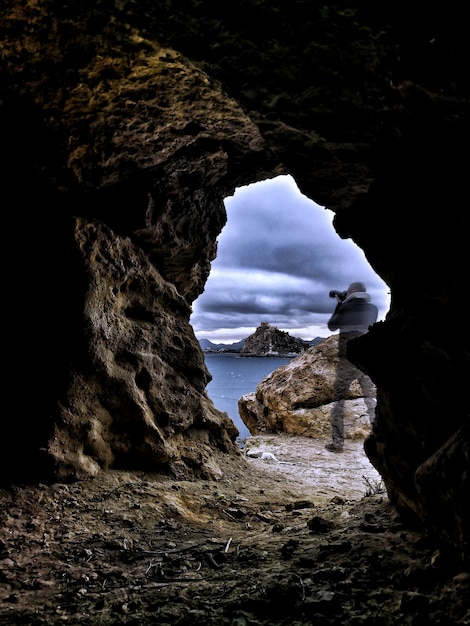 Photo man photographing seen through cave