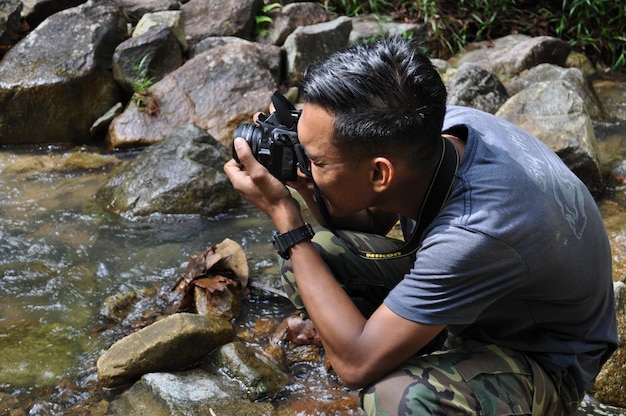 Photo man photographing through camera by stream