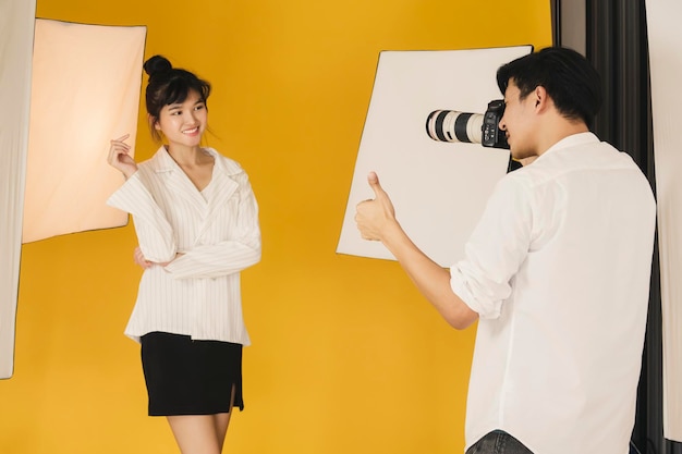 Man photographing woman while standing in studio