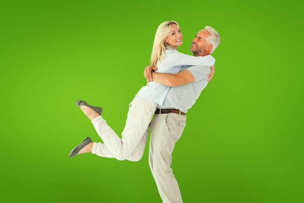Фото Мужчина поднимает своего партнера, обнимаясь здесь против зеленой виньетки