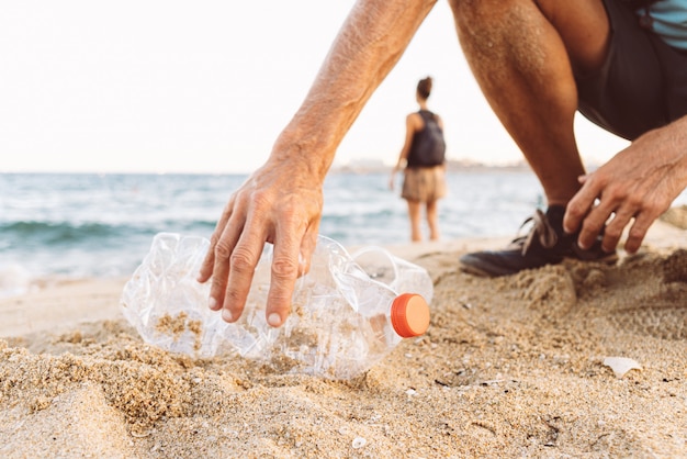 写真 ビーチでプラスチックを拾う男