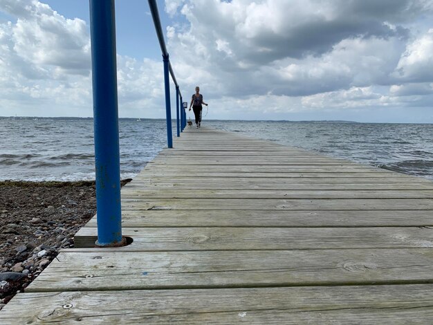 Man on pier over sea against sky