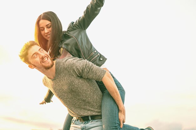 Photo man piggybacking girlfriend against sky