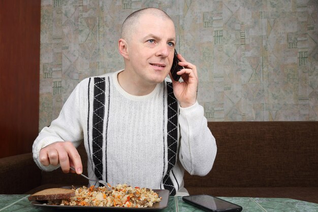 Man pilaf eten en praten over een mobiele telefoon