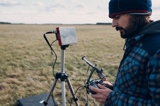 Photo man pilot controlling quadcopter drone with remote controller pad.