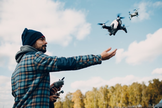 Man pilot controlling quadcopter drone with remote controller pad