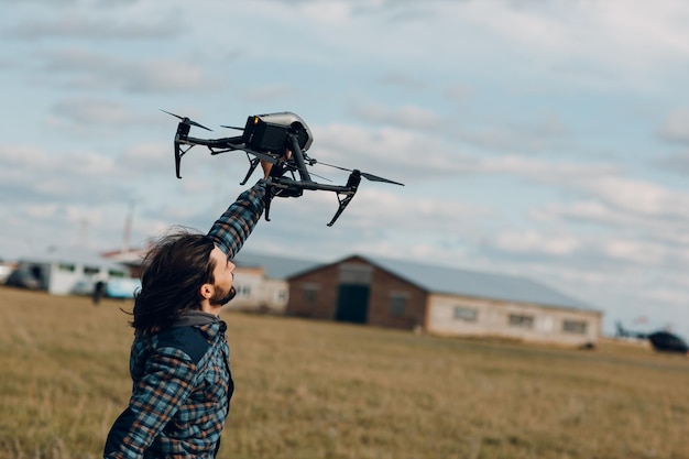 Man pilot holding quadcopter drone in hands at outside field