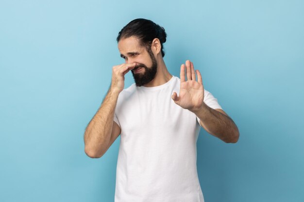 Man pinching her nose to hold breath and showing stop gesture disgusted by unpleasant odor fart