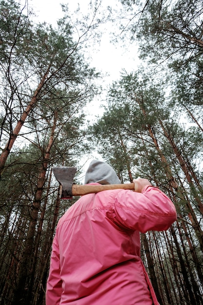 Man in pink jacket in forest with axe