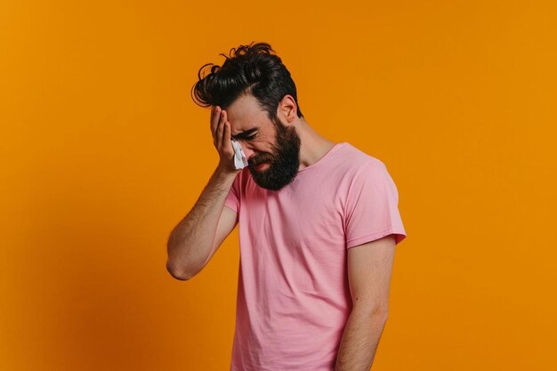 Photo a man in a pink shirt holding a cell phone to his face