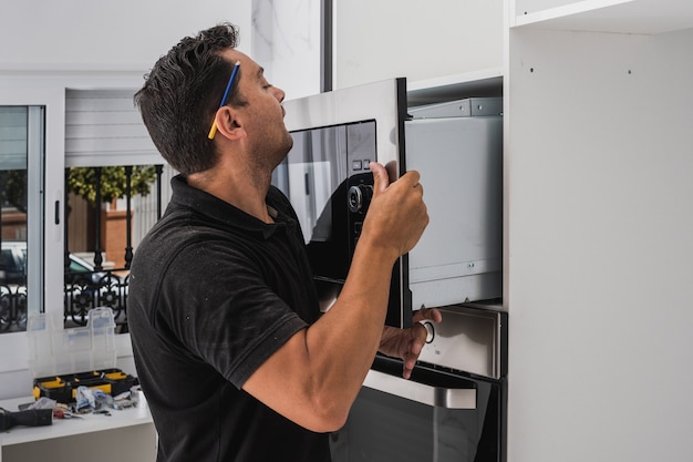 Photo man placing a microwave inside the hole of a new kitchen cabinet