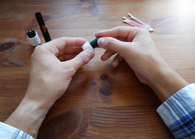 Photo a man in a plaid shirt cleans an electronic modern cigarette